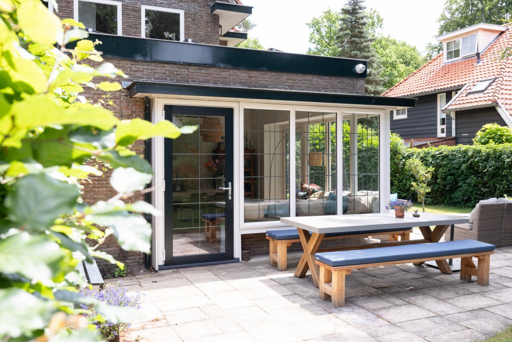 Kunststof kozijnen serre wit met donkerblauw achterdeur van kunststof met loodroedes in jaren 30 woning in Baarn